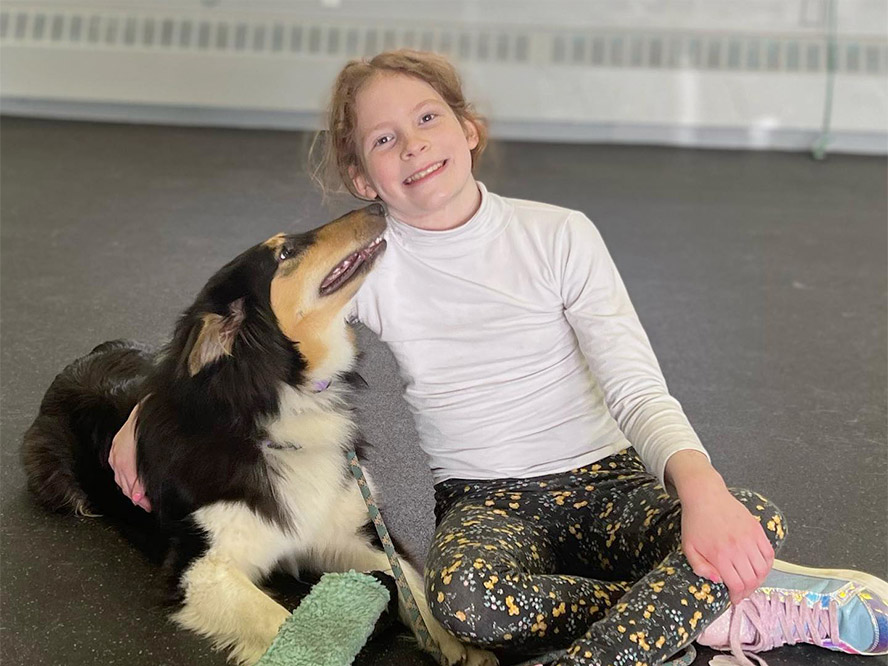 Child sitting on the floor with her dog at the Maine Dog Training Company training center