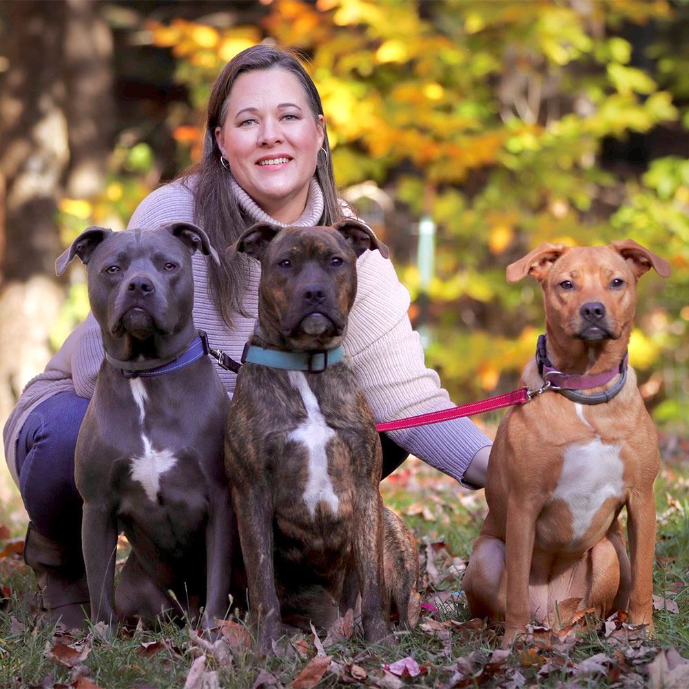 MDTC Day School manager Amanda Atwood sitting with her three dogs